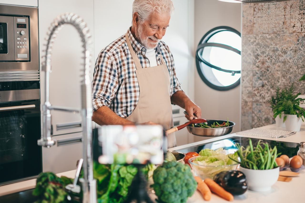 Adult man over 55 at a kitchen counter moving processed food aside while choosing whole foods for better knee health.