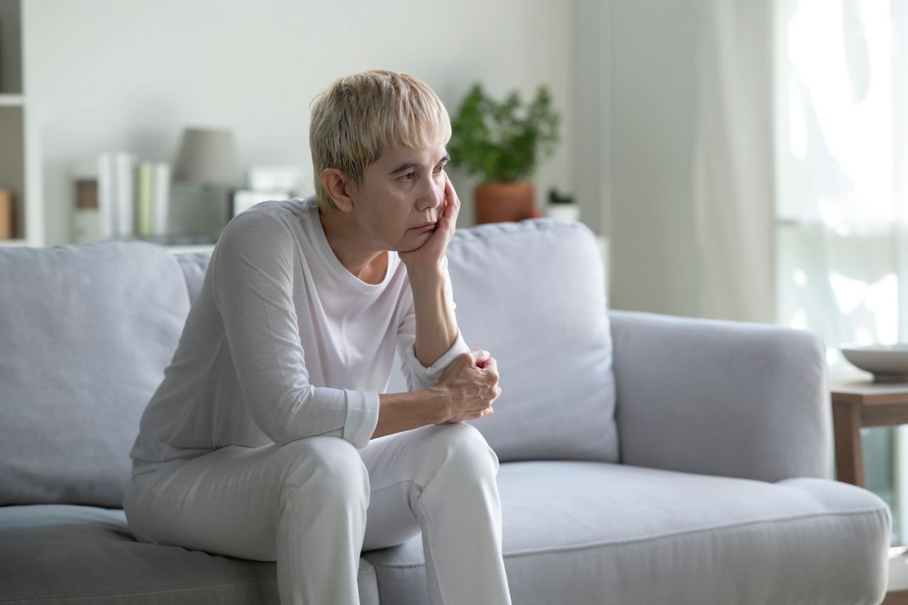 Adult woman over 55 sitting in an armchair after poor sleep illustrating how inflammation and sleep quality over 55 affect morning energy and joint comfort.