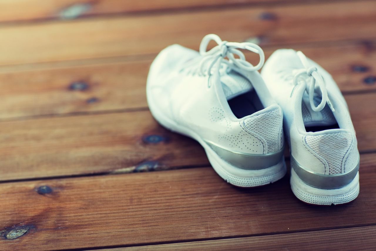 Walking shoes beside a front door in morning light representing the moment of hesitation that pain catastrophizing creates for adults walking with knee pain.