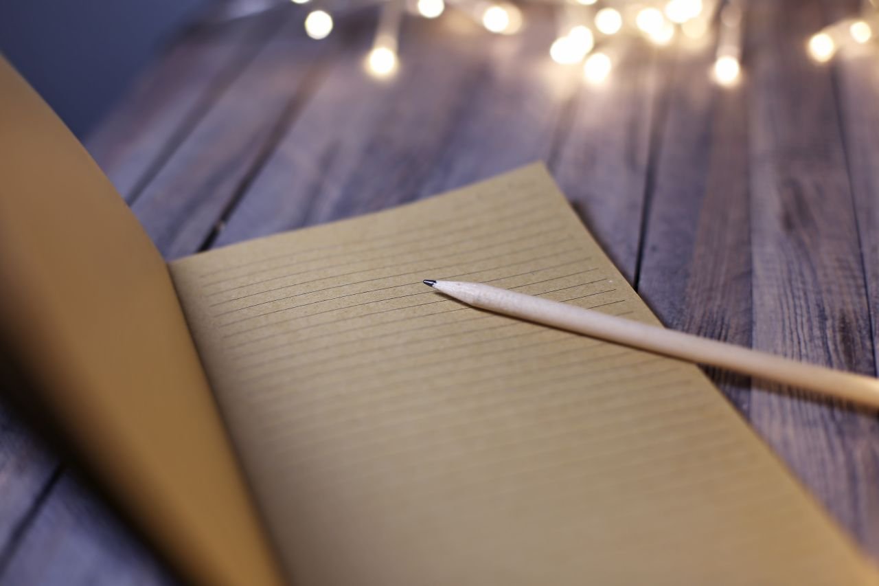 Open notebook with checkmarks on a table representing the daily feel-check practice that builds mindset for walking with knee pain over time.