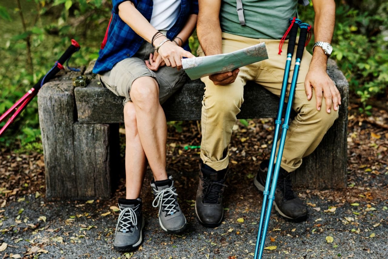 Walking poles resting against a park bench beside a water bottle representing the daily walking habit that poles help adults over 60 maintain.