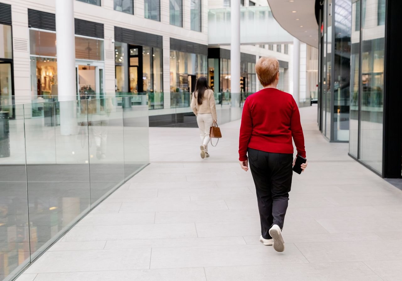 Figure walking indoors along a covered corridor on a rainy day showing how to keep moving when knees hurt in wet weather.