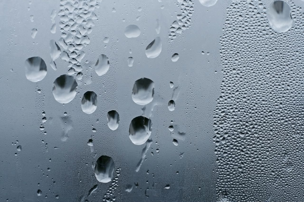 Rain running down a window pane representing the barometric pressure changes that explain why knees hurt when it rains for adults with OA.